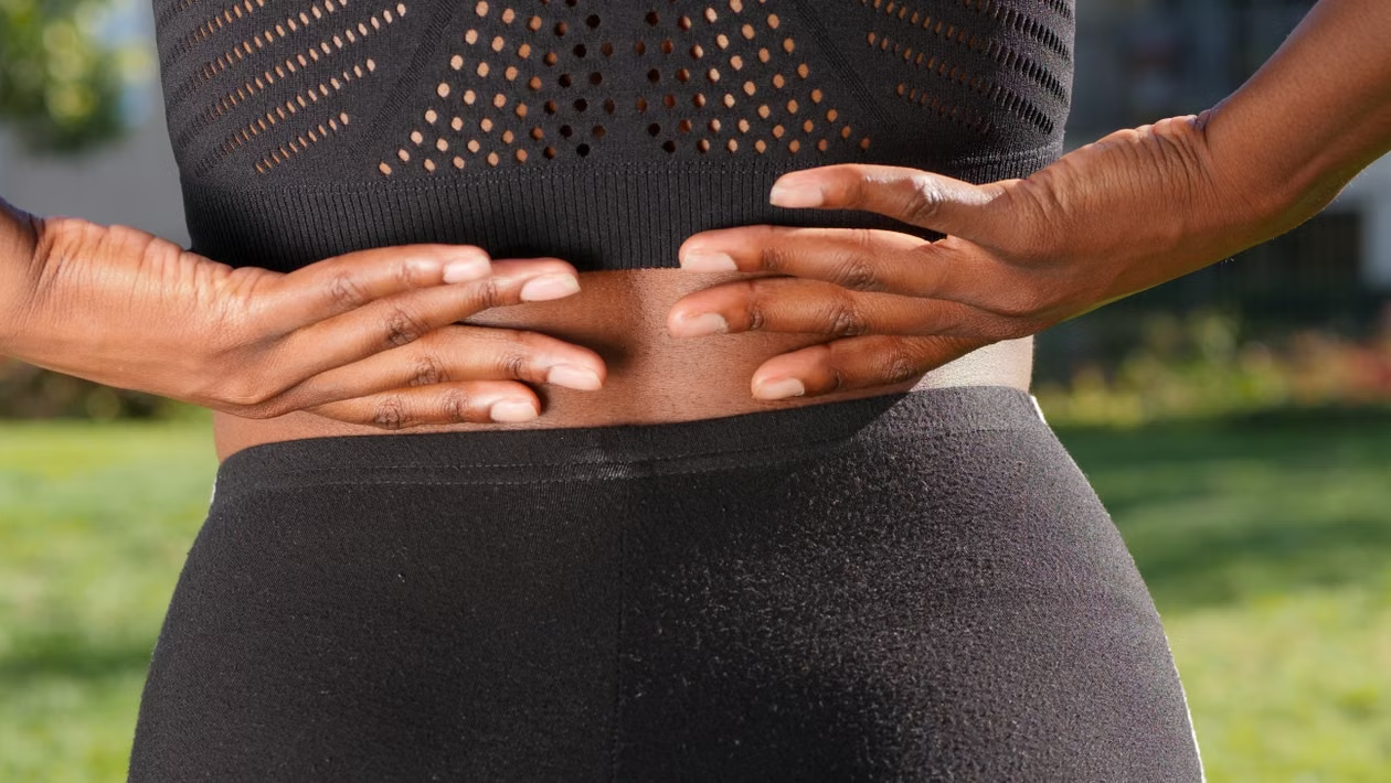 Person holding their lower back while experiencing discomfort