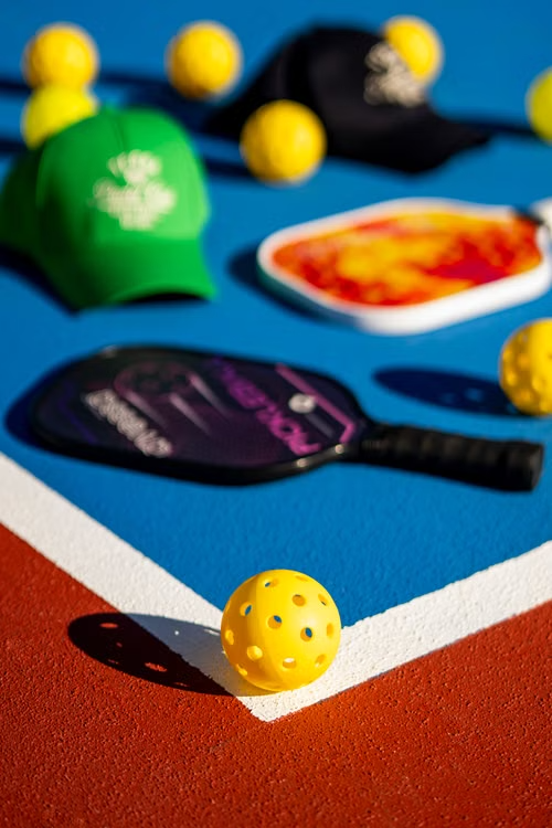 Pickleball paddles and balls arranged on a court